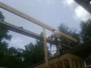 Carpenter setting a ridge beam over a new addition frame — Ice Dam Removal by Roofing Brothers in Montara