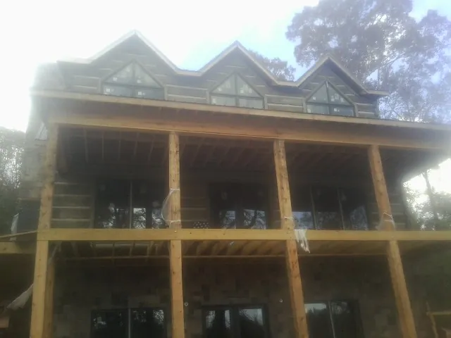 Dormers and porch framing on a large log home under construction — Roof Coating work by our crew in Montara