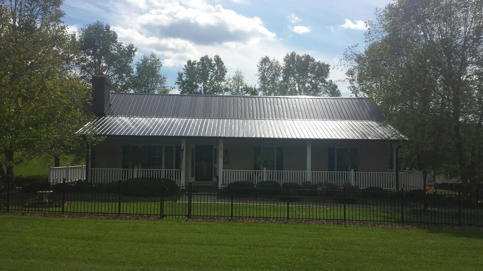 Gray metal roof on a brick ranch with a full width front porch — Gutter Guard Installation work by our crew in Montara