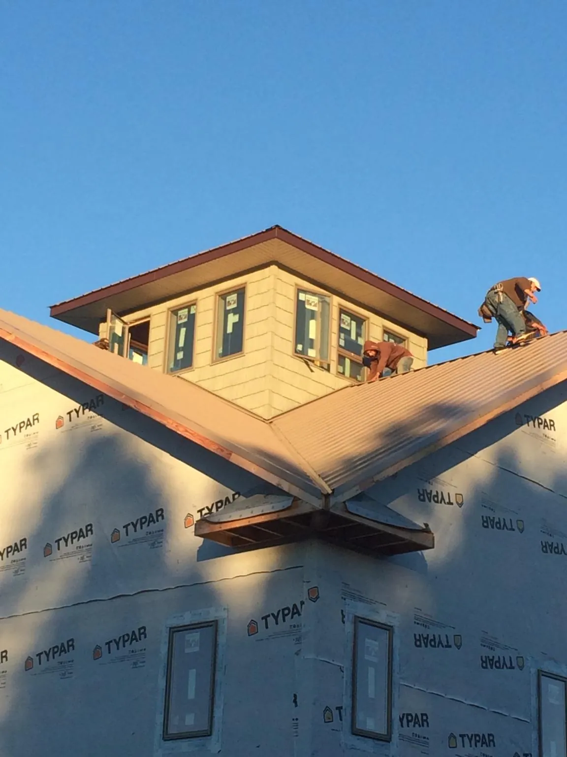 Roofers working around a rooftop cupola on a new metal roof at sunset — Roof Waterproofing in Montara by Roofing Brothers